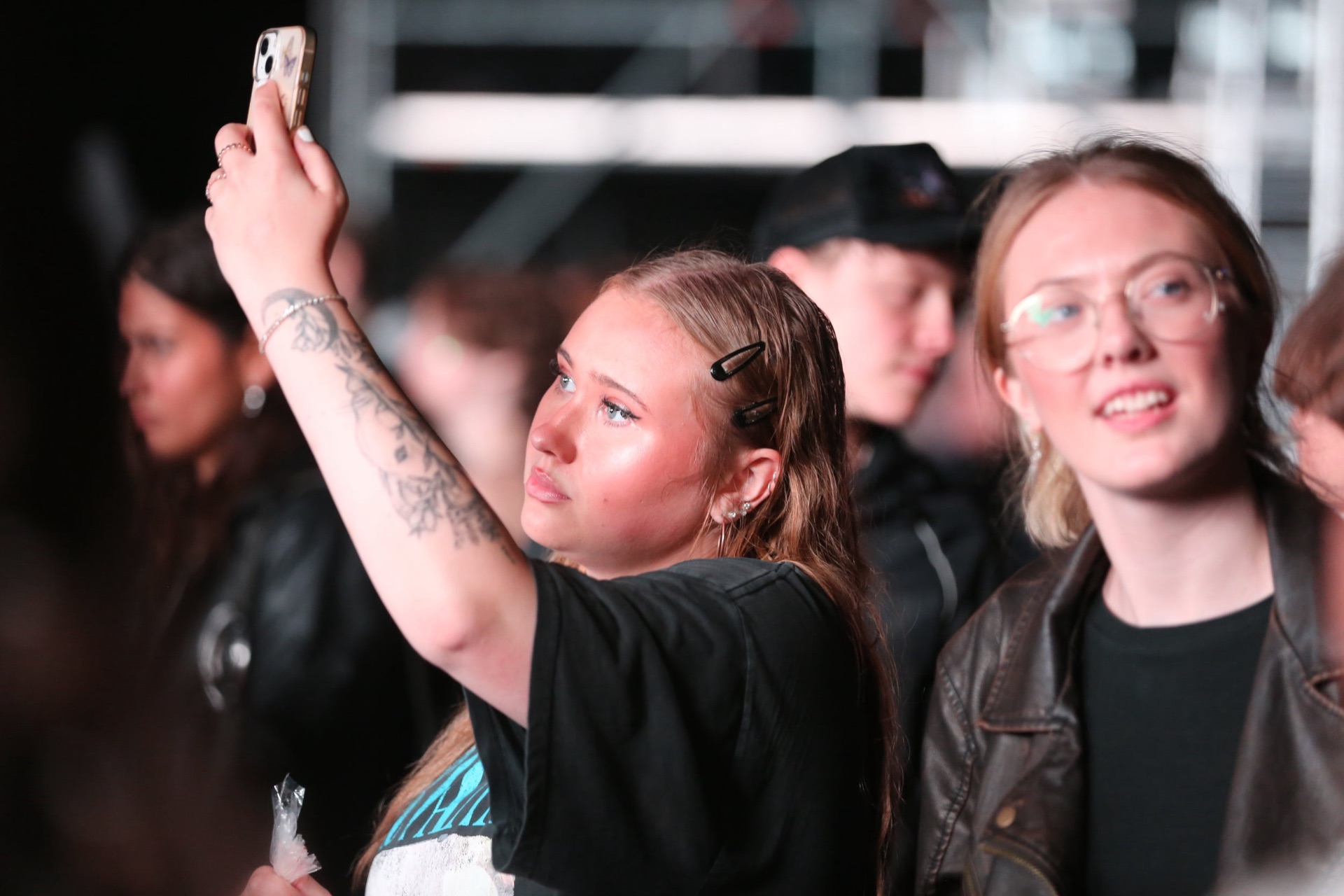 Fans filming a concert on their phones in the crowd