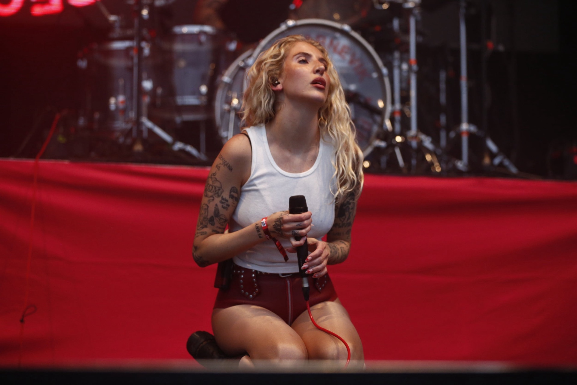 Vocalist kneeling on stage during a festival set